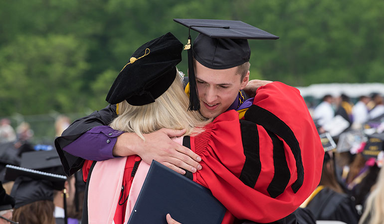 Student hugging professor at graduation