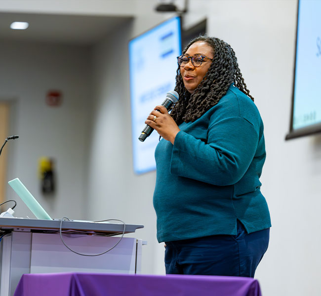 A women presenting from behind a podium