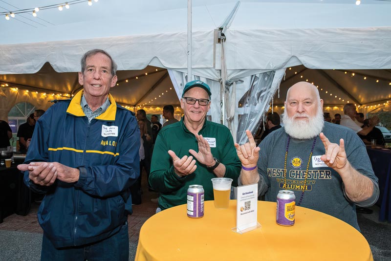 group of wcu family weekend visitors smiling and throwing up the ram symbol around a table