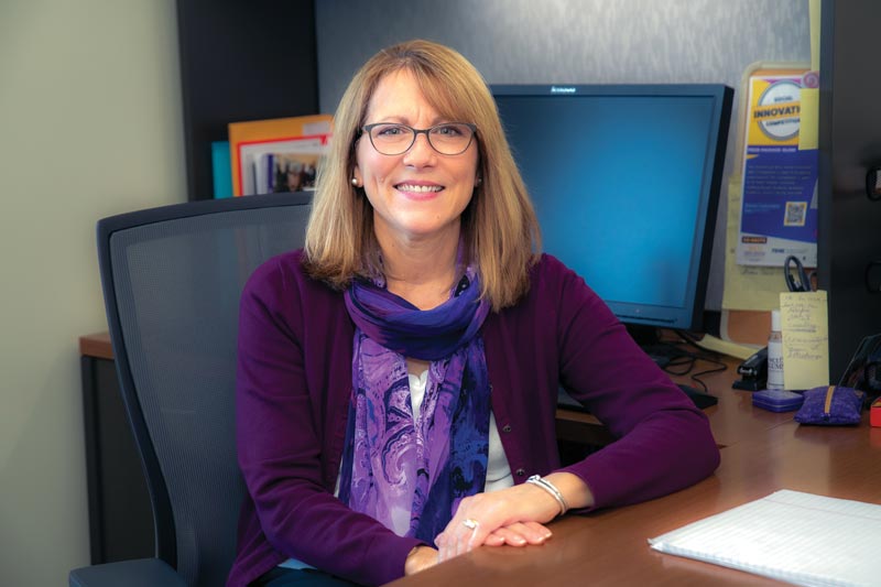 Sue Fiorentino sitting at a desk looking at the camera.