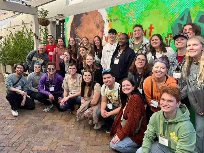 Group posing in front of mural