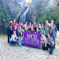 Group posing in nature with the WCU flag