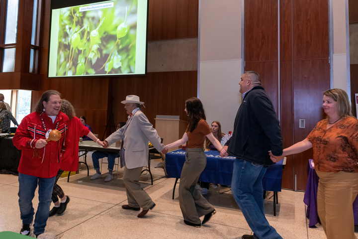 The Malàxkwsitkan (Bean Dance) moves through the ballroom while the ongoing 'Life in the Gordon' slideshow is projected behind them