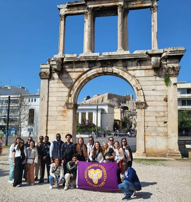 WCU students on a study abroad trip holding a WCU purple sign